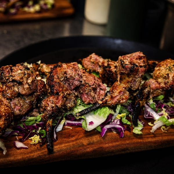 Grilled lamb chops with herbs and spices, served on a bed of fresh lettuce and red cabbage.