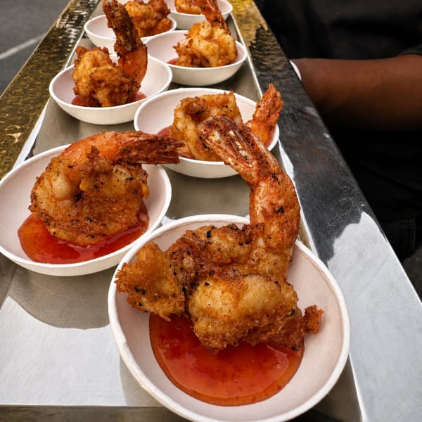 A tray of crispy fried shrimp appetizers with sweet chili sauce, ready to be served.