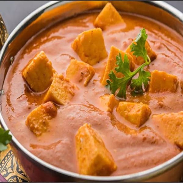 Paneer butter masala, an Indian dish with paneer cubes in a creamy orange sauce, garnished with cilantro.